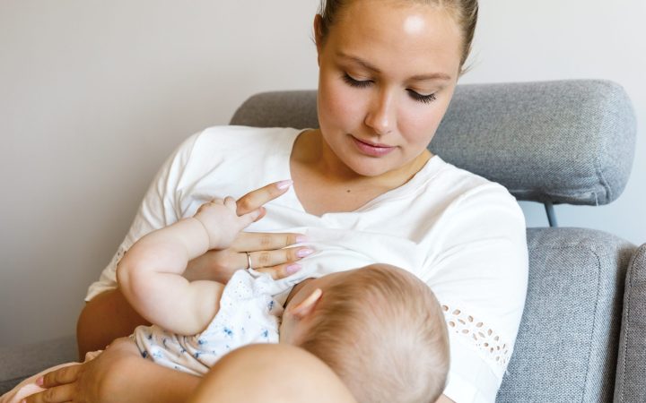 caring-young-mother-breastfeeds-baby-girl-PLXNEU7