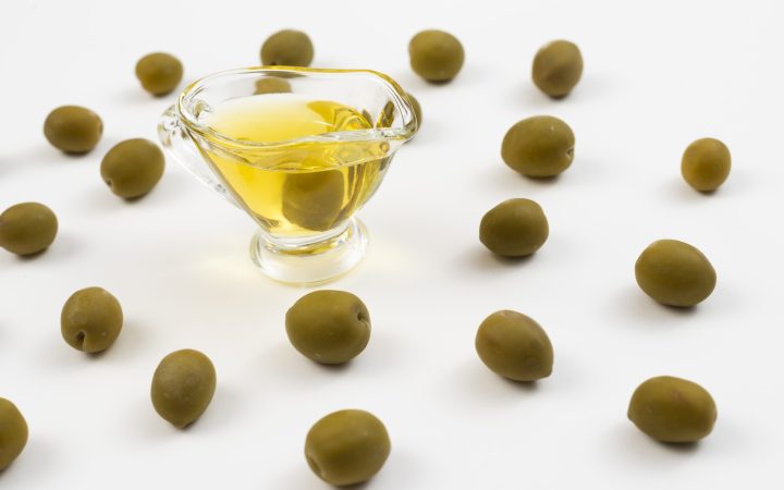 glass-filled-with-oil-surrounded-by-green-olives