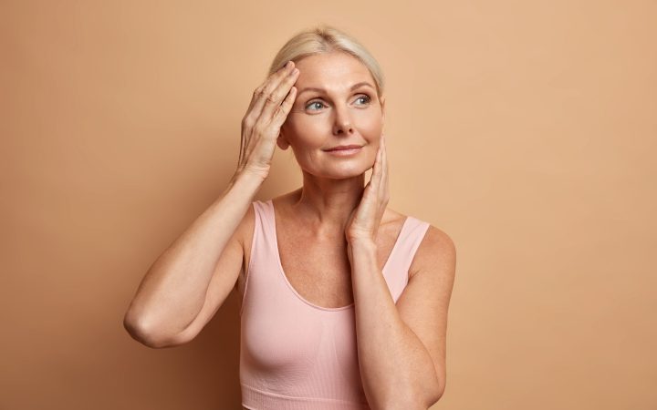 portrait-mature-elderly-european-woman-touches-face-gently-has-perfect-skin-looks-thoughtfully-away-enjoys-her-soft-complexion-cares-about-appearance-satisfied-after-anti-aging-procedure