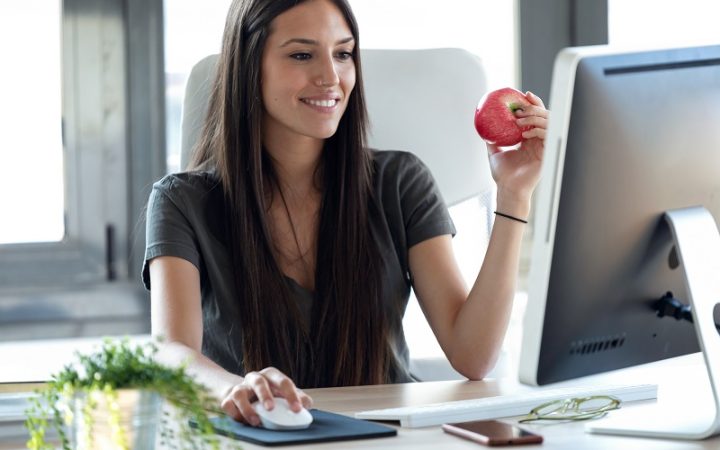 smiling-young-business-woman-eating-a-red-apple-wh-5CBXKQ5