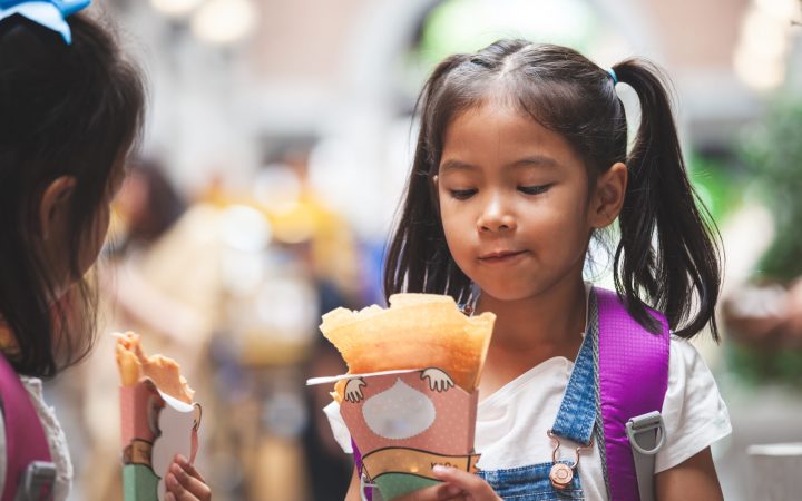 two-cute-asian-child-girls-with-backpack-eating-pancake-together-after-school-school